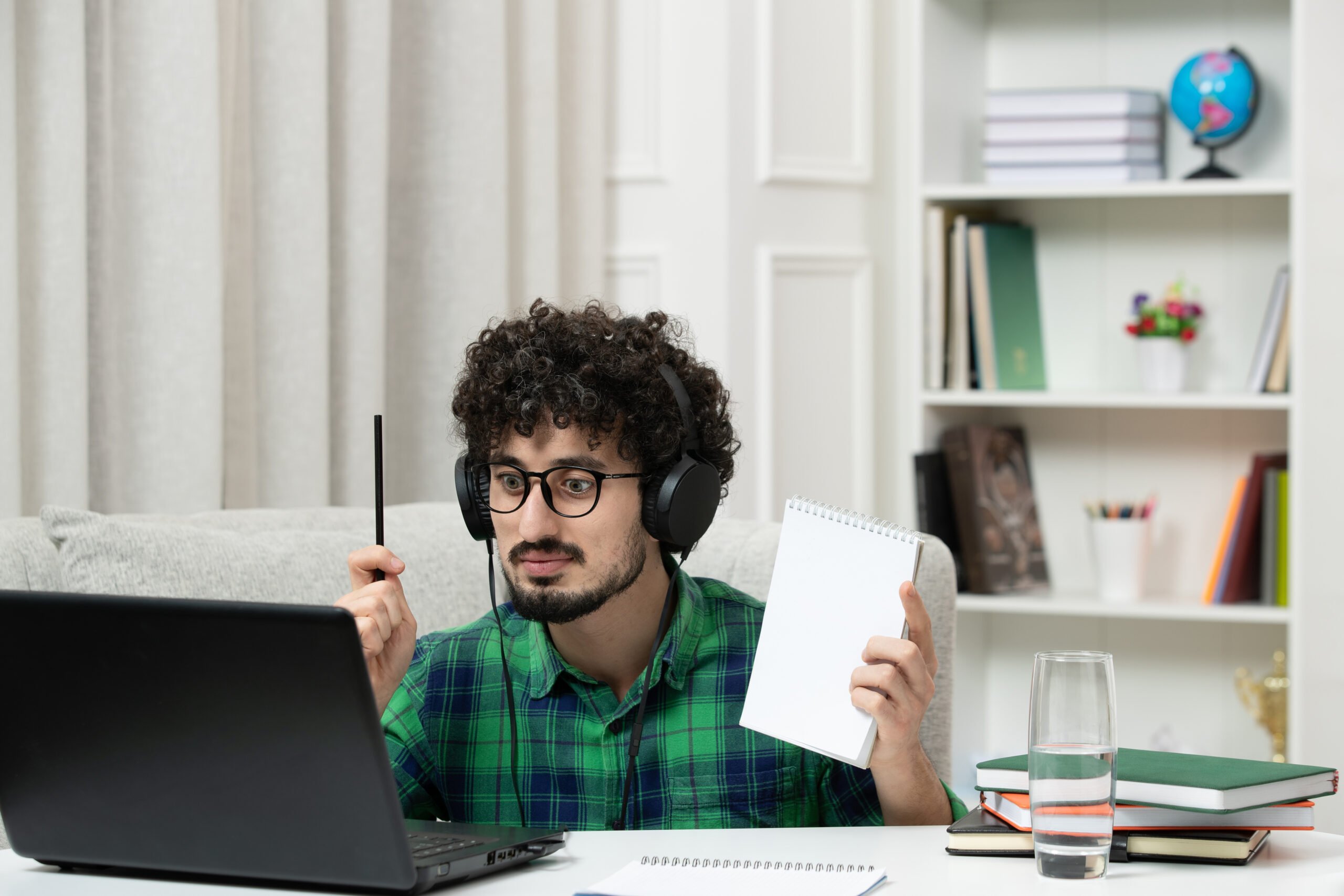 Aprender inglês do zero: dicas e principais desafios | Foto de um homem com fone e um bloco de notas estudando online | IP School