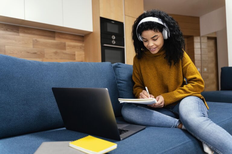 Sotaque inglês: dicas para melhorá-lo | Foto de uma mulher estudando com notebook e um caderno sentada no sofá | IP School